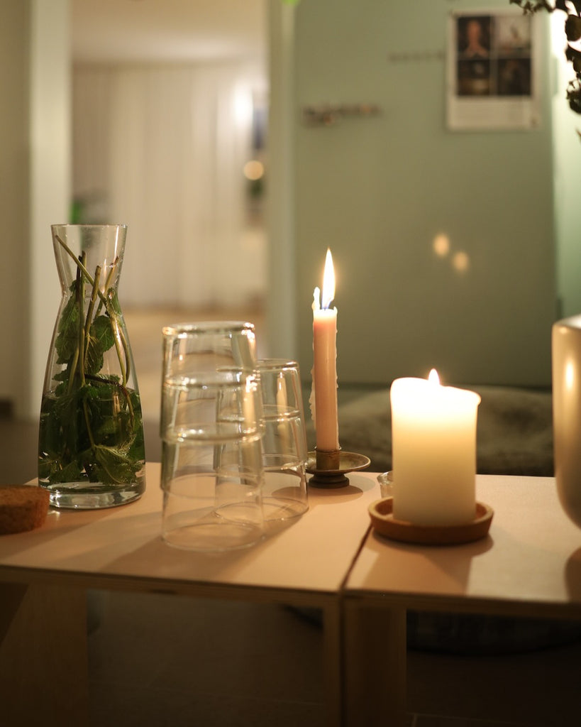 Sitzecke vor dem Yogaraum im LE MOUV Studio mit Wasser, Tee und Kerzen auf dem Tisch, stilvoll und gemütlich eingerichtet.