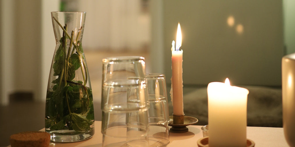 Sitzecke vor dem Yogaraum im LE MOUV Studio mit Wasser, Tee und Kerzen auf dem Tisch, stilvoll und gemütlich eingerichtet.