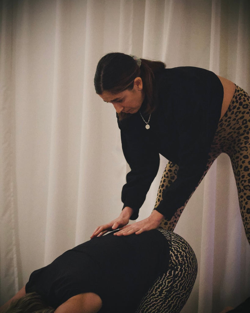 Katharina Klinkert, Yogalehrerin im LE MOUV Studio, korrigiert eine Schülerin in der Haltung des Kindes anatomisch korrekt."